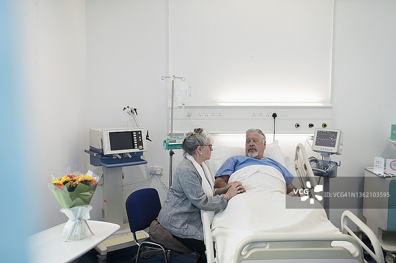 安慰在医院病床上休息的丈夫的老年妇女图片素材