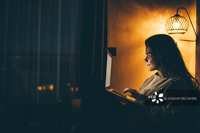 女人晚上在家使用笔记本电脑图片素材