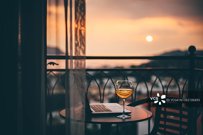 阳台上日落时分的葡萄酒和笔记本电脑图片素材