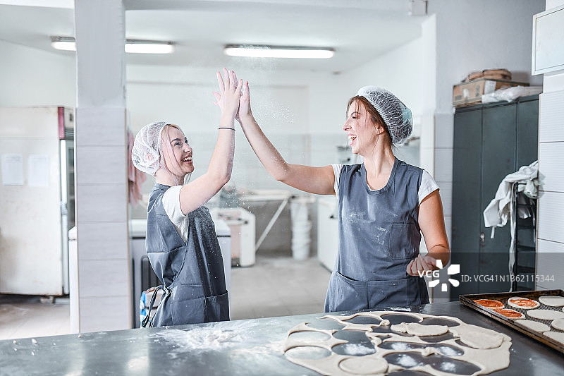 在面包店做披萨时击掌的可爱微笑图片素材