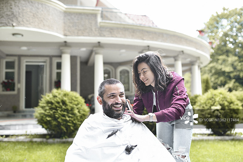 在后院被女友理发时微笑的男人图片素材