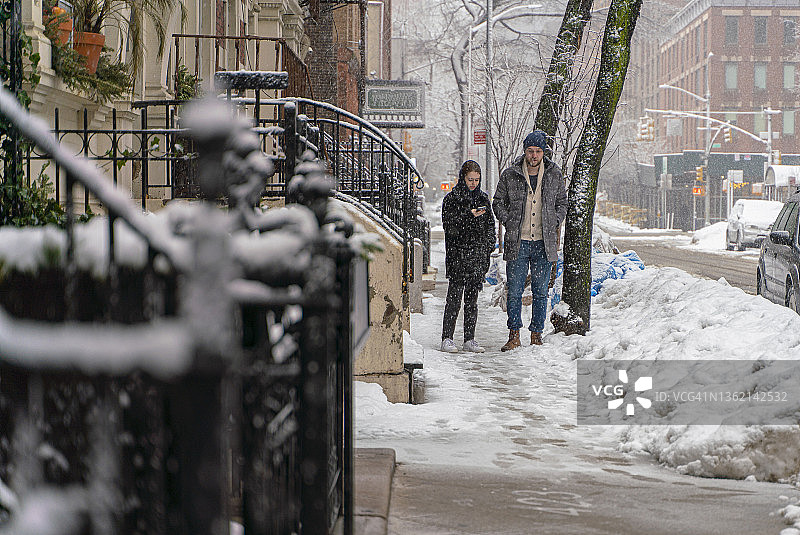 冬季雪后，年轻情侣在空旷的城市街道上漫步图片素材