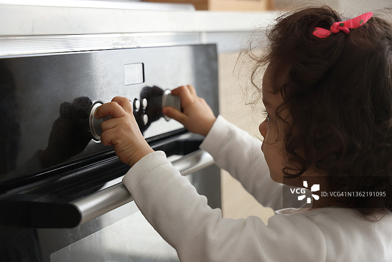 小女孩转动烤箱按钮图片素材