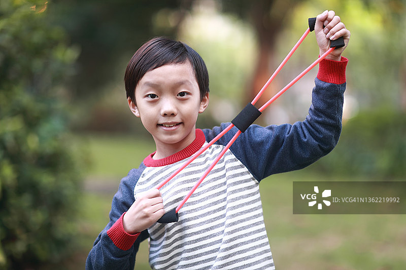快乐的男孩用弹性健身带做运动图片素材
