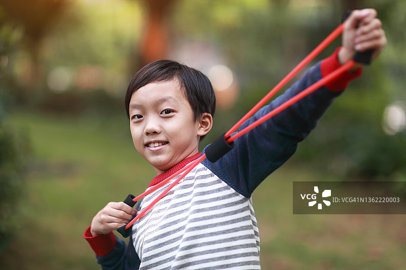 快乐的男孩用弹性健身带做运动图片素材