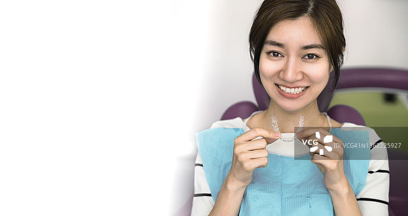 年轻女人拿着隐形牙齿矫正器图片素材