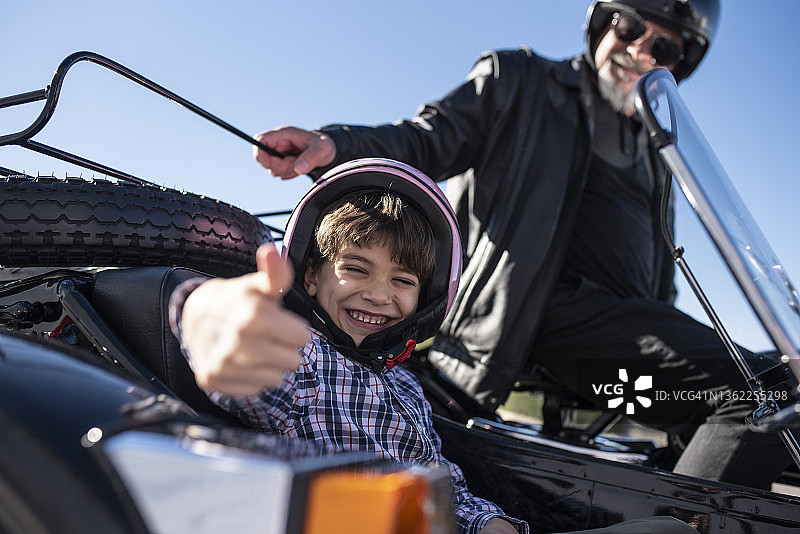 坐在爷爷边车里，对着镜头做OK手势的小男孩图片素材