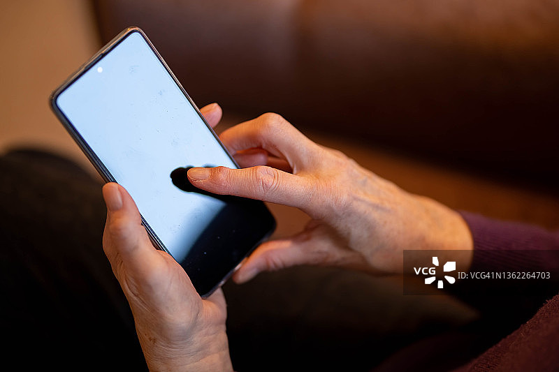 年长妇女手持智能手机图片素材