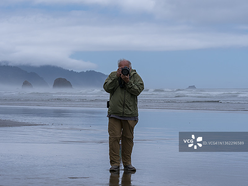 在 Cannon 海滩的年长摄影师图片素材