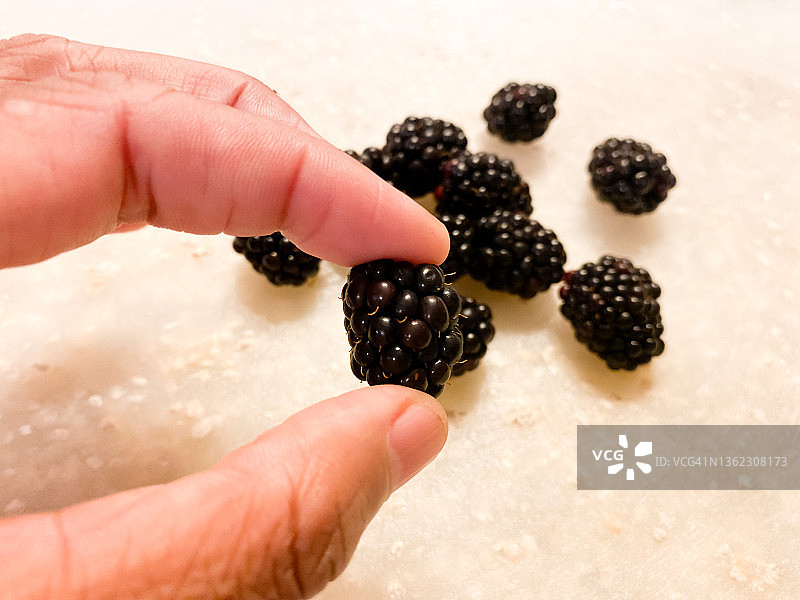 非裔美国妇女手拿黑莓，背景是一堆黑莓图片素材