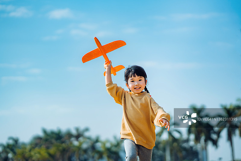 快乐的亚洲小女孩在户外玩耍飞机玩具图片素材