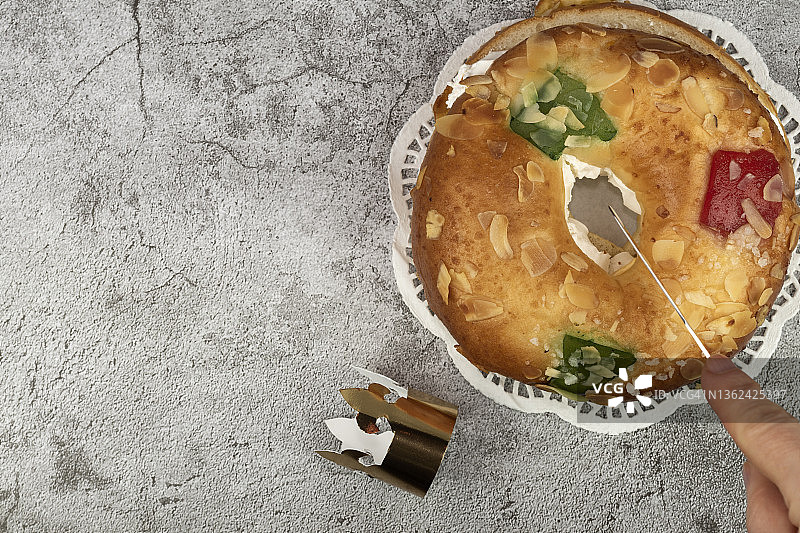 灰色背景下的西班牙主显节蛋糕，一只手正在切一块。直接上方有复制空间。图片素材