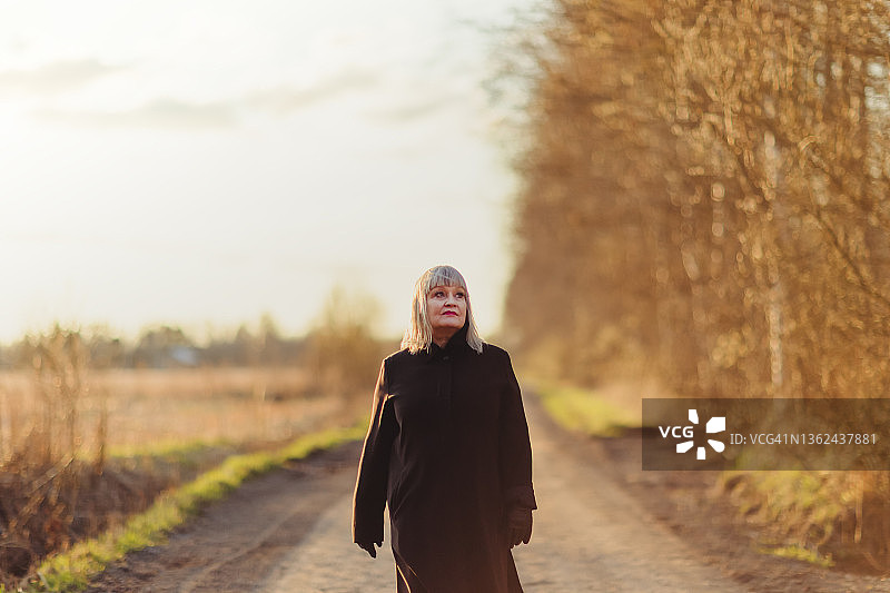 美丽的年长女人在日落时分在户外散步图片素材