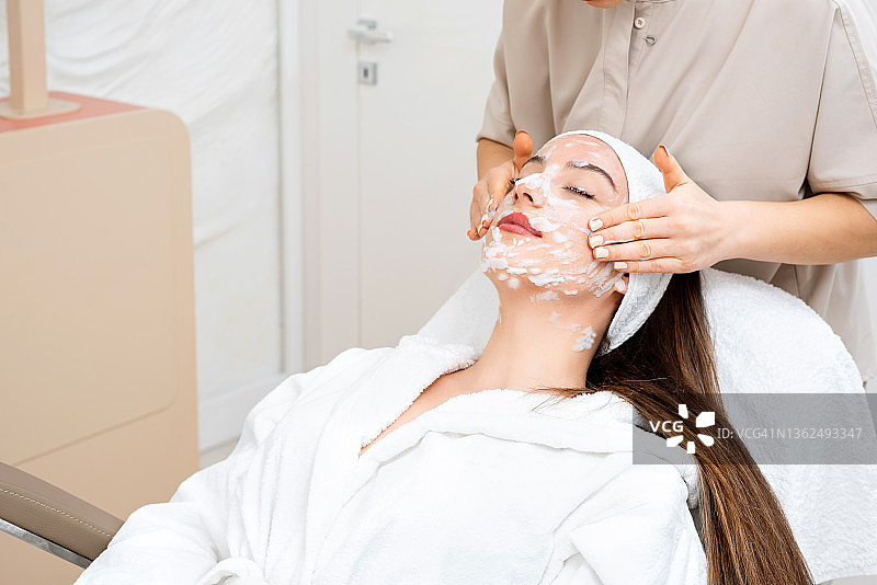 皮肤科医生用清洁泡沫清洁女性面部皮肤。图片素材