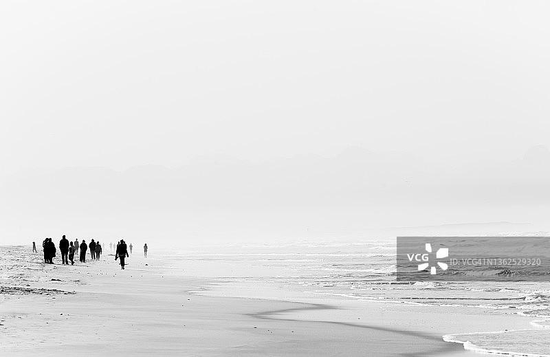 徒步者在海滩水边行走图片素材