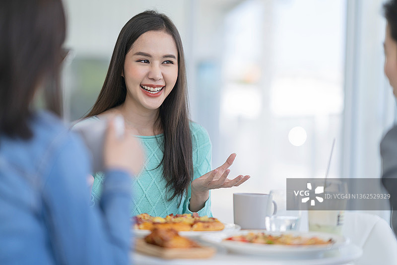 亚洲女性在咖啡馆与朋友交谈图片素材