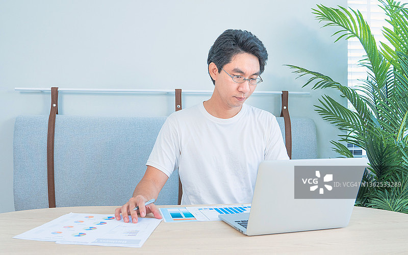 年轻商人居家办公，使用笔记本电脑和纸质文件进行在线视频会议图片素材