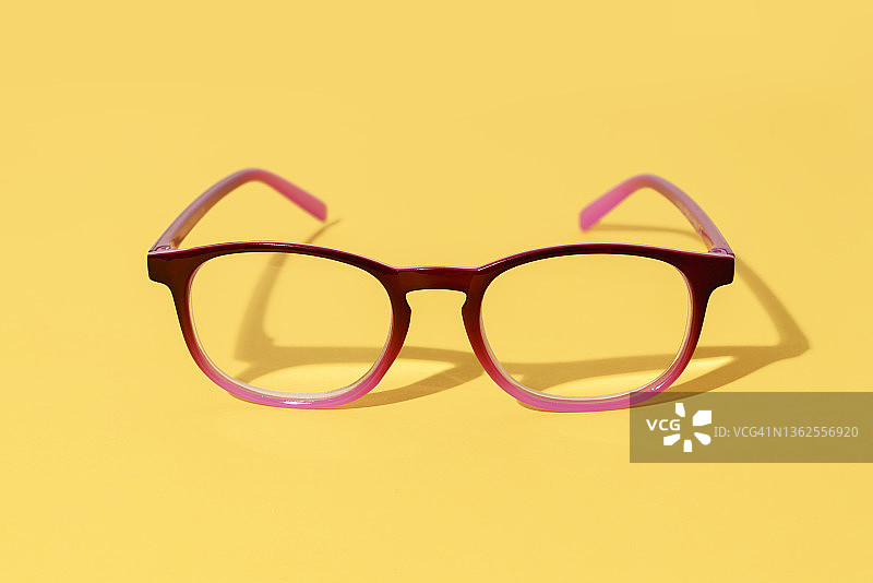 黄色背景上的洋红色现代眼镜图片素材