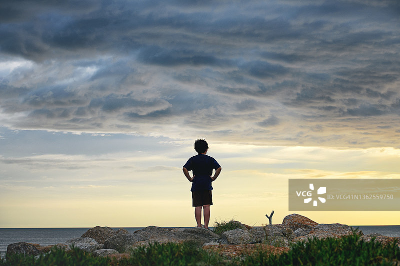 男孩看着暴风雨前的海湾景色图片素材