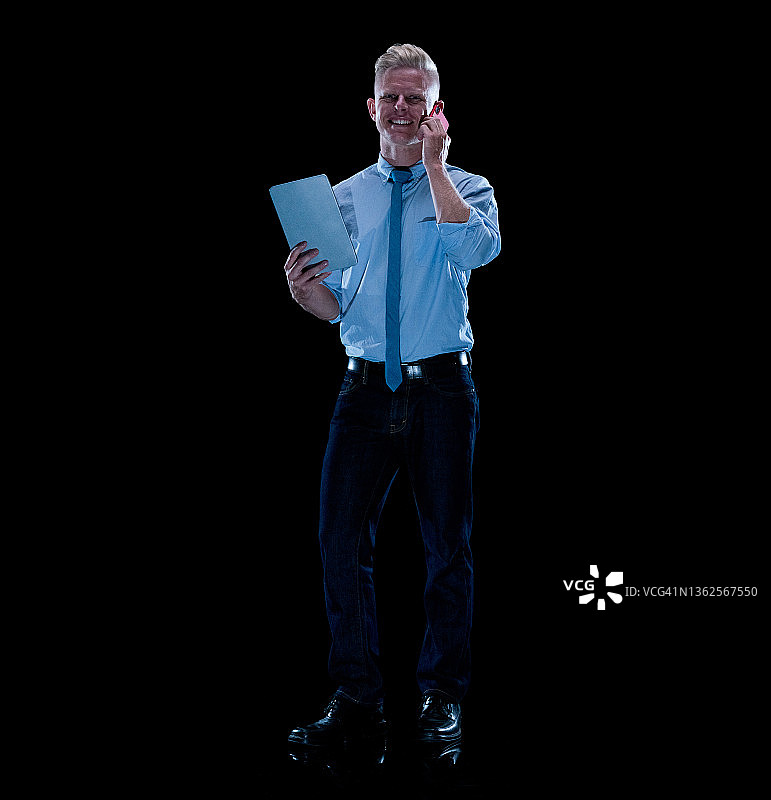 站在黑色背景前，穿裤子使用智能手机的白人男商人图片素材