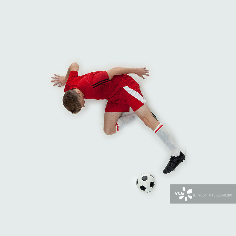 站在白色背景前，踢足球的年轻白人男性足球运动员图片素材
