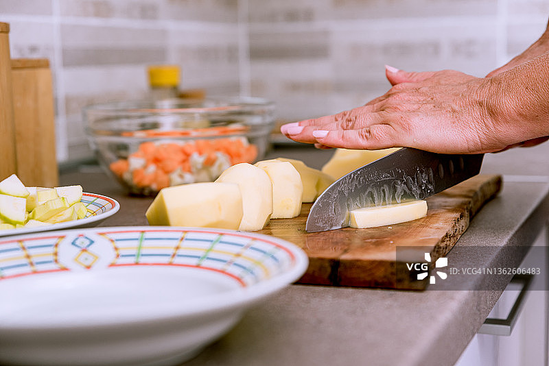 在厨房柜台上切菜，准备健康纯素餐的女人图片素材