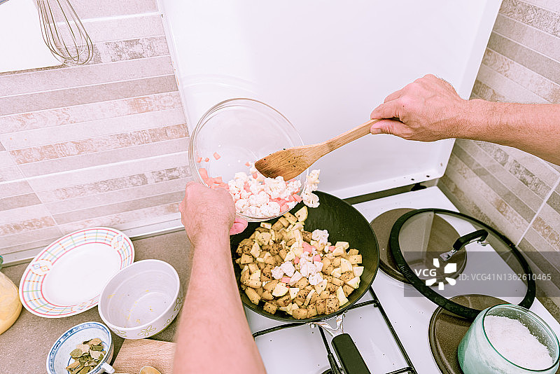 在家中厨房用煎锅准备蔬菜的男人图片素材
