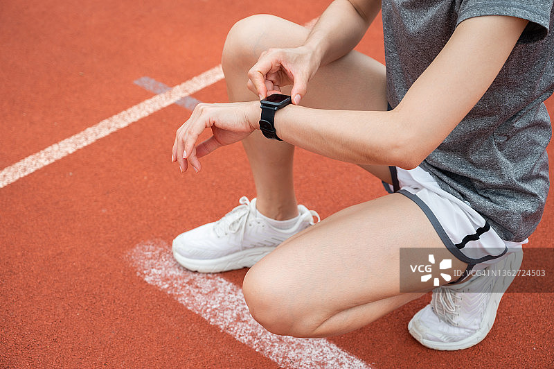 跑步者在跑步时查看智能手表上的健康状况和健身进度图片素材