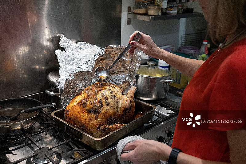 圣诞节时给火鸡涂油的女人图片素材