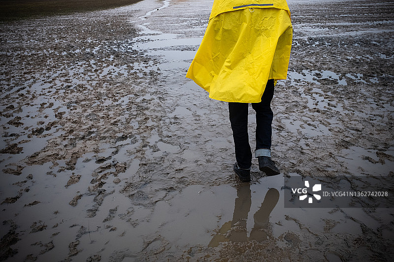青少年男孩在海滩上穿着黄色外套的背面图图片素材