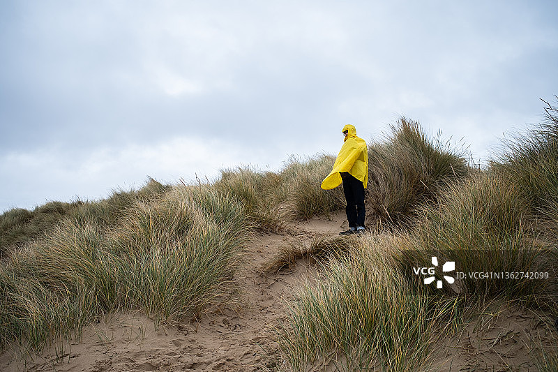 青少年男孩在海滩上穿着黄色外套的背面图图片素材