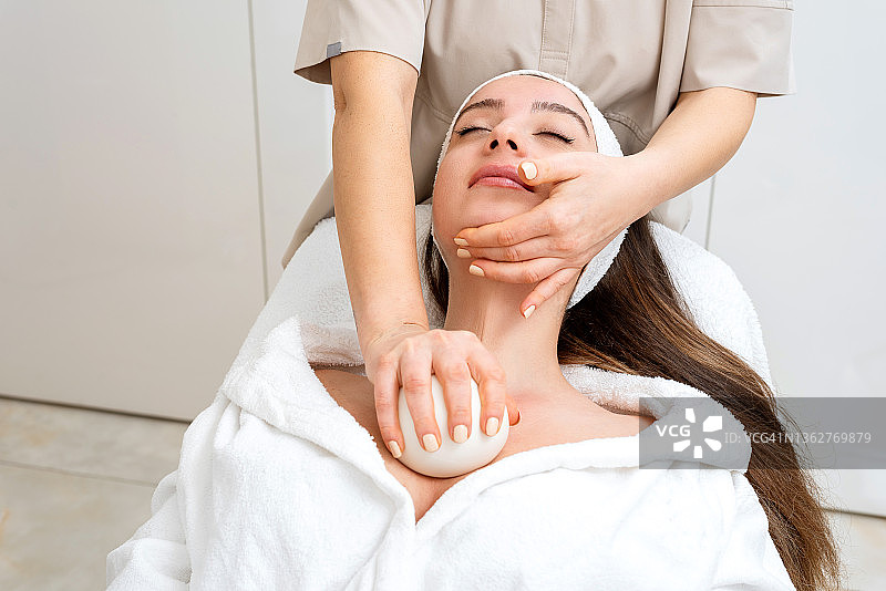 女皮肤科医生用面部按摩球护理美丽女性的皮肤图片素材