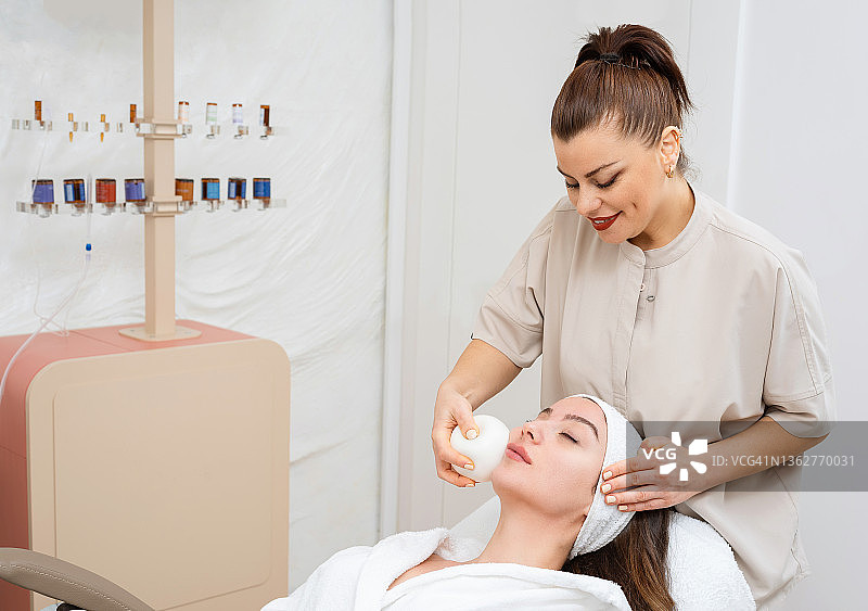 女皮肤科医生用面部按摩球护理美丽女性的皮肤图片素材