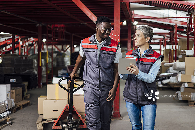 在仓库里搬运箱子的非裔美国工人和经理图片素材