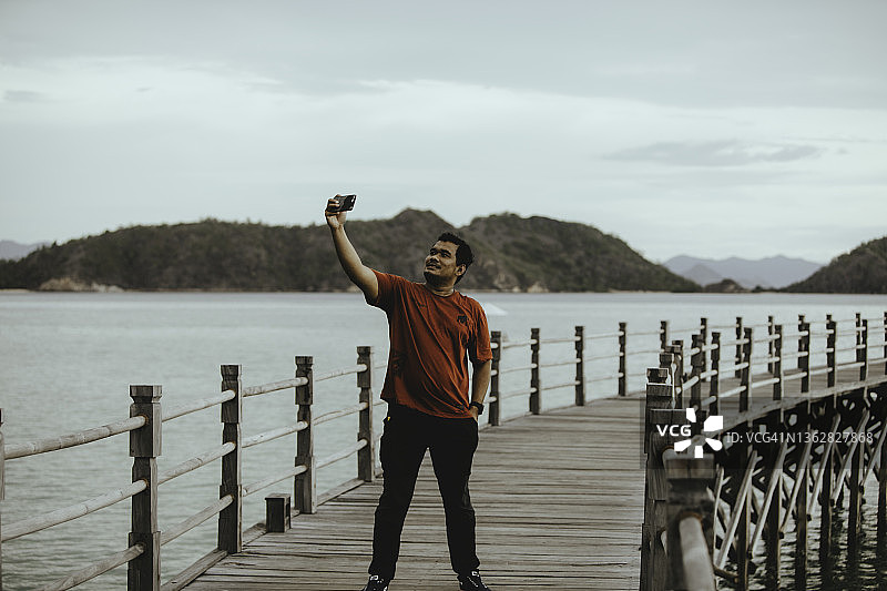 男人站在木板路上使用手机图片素材