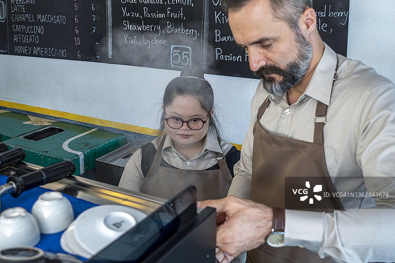一位患有唐氏综合征的女士在餐厅与一位年轻男子一起工作图片素材
