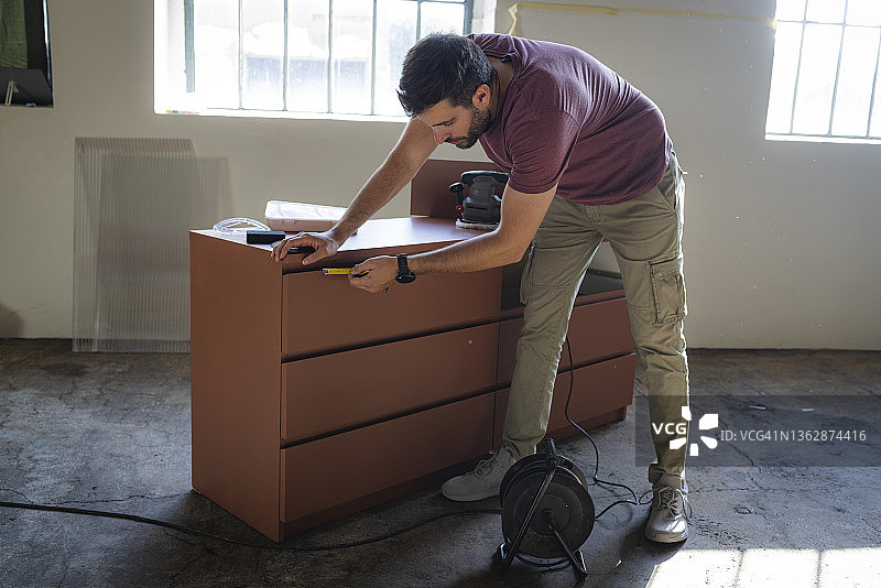 白人木匠用卷尺测量木制梳妆台图片素材