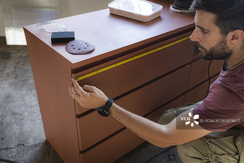 白人木匠用卷尺测量木制梳妆台图片素材