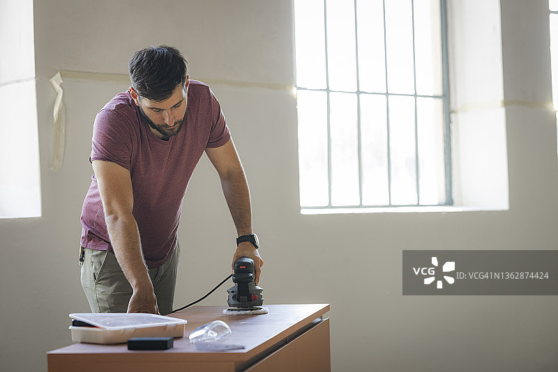 制作家具的英俊白人建筑师，打磨木制抽屉柜图片素材