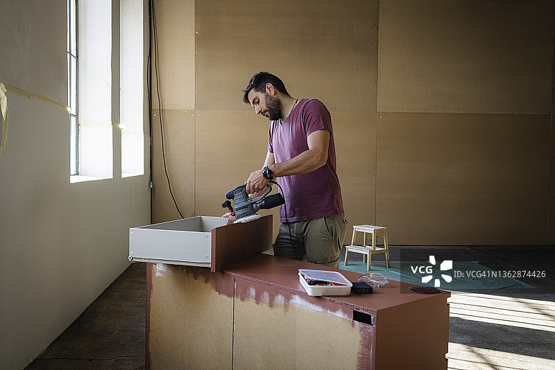 制作家具的英俊白人建筑师，打磨木制抽屉柜图片素材