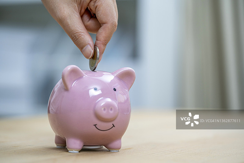桌上大量发票的特写。财务统计文件，水电费账单，家庭付款。强调一个女人把硬币放进存钱罐的手。图片素材