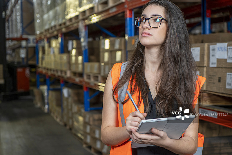 戴安全帽的职业女工人在零售仓库中使用平板电脑检查库存图片素材