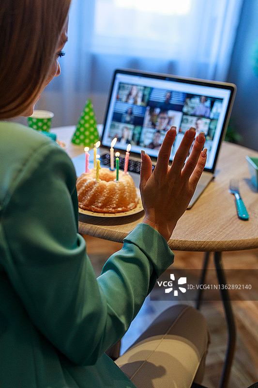 少女在视频通话中向朋友挥手庆祝生日图片素材