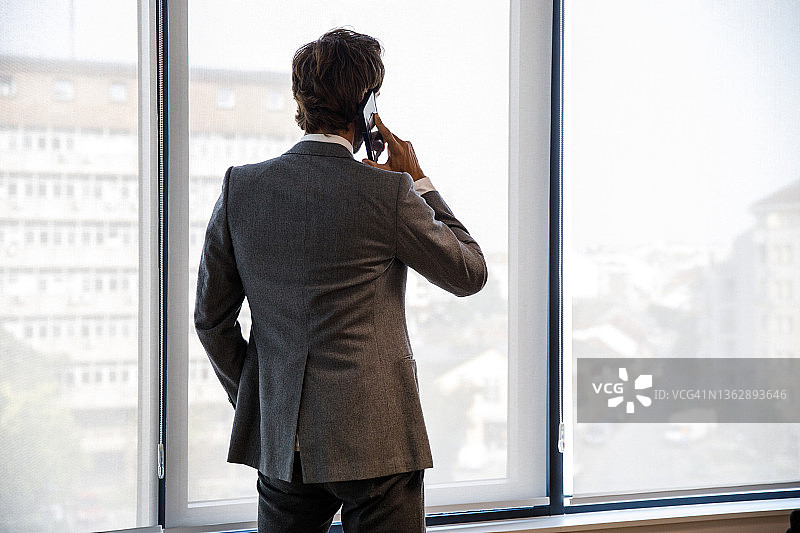 商务人士在电话会议中望向窗外图片素材