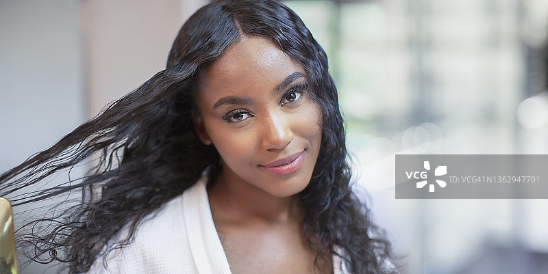 自信美丽的年轻女子梳理黑色长发的肖像图片素材