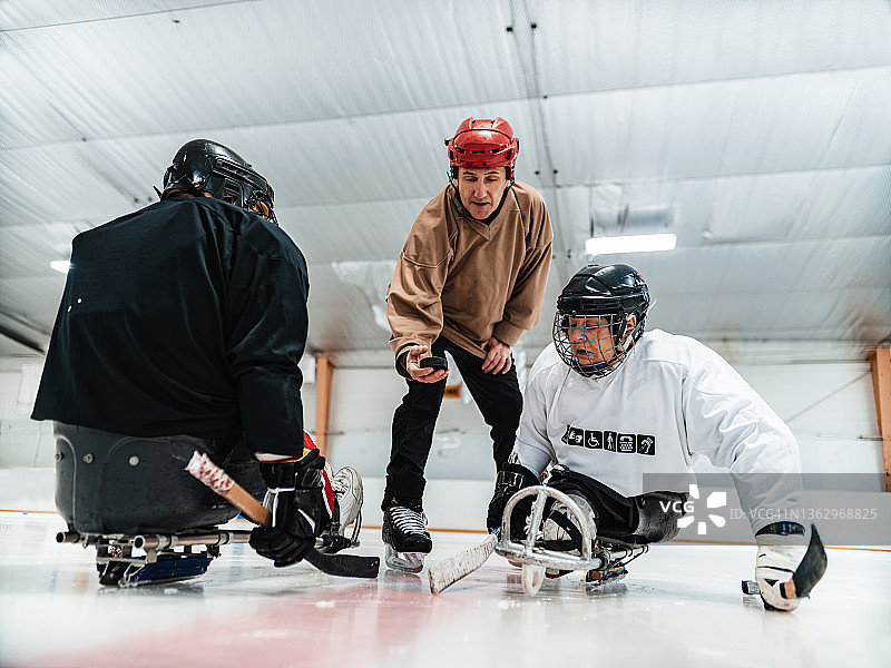 残疾拉丁裔中年妇女和同伴及教练一起练习冰橇曲棍球图片素材