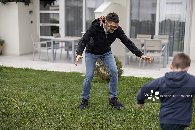 蒙眼父亲在后院与儿子玩捉迷藏图片素材