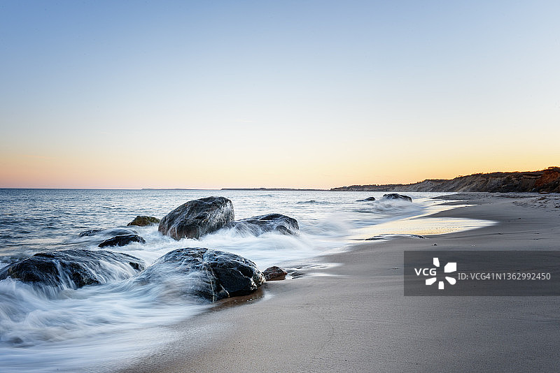 海浪拍打空旷沙滩上的岩石图片素材