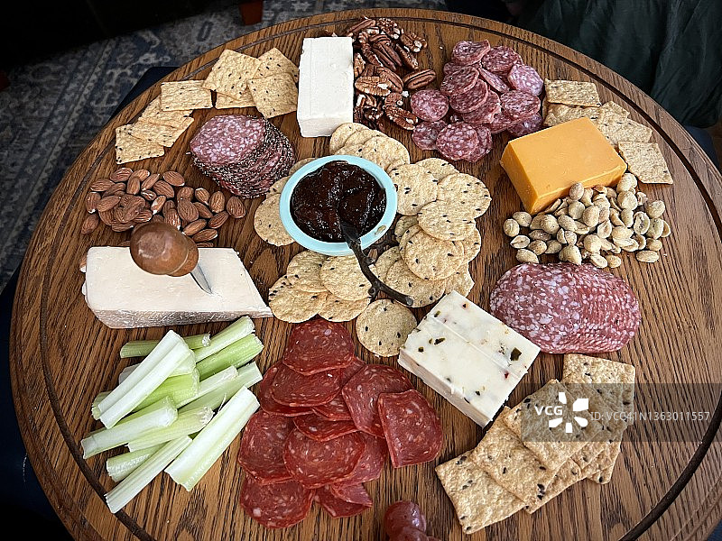 从上方拍摄的砧板上，有切片的熟食肉类、橄榄、坚果和奶酪图片素材