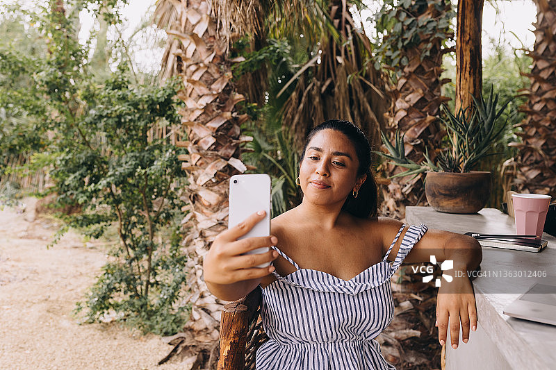 一边用电脑工作一边自拍的年轻墨西哥女性图片素材